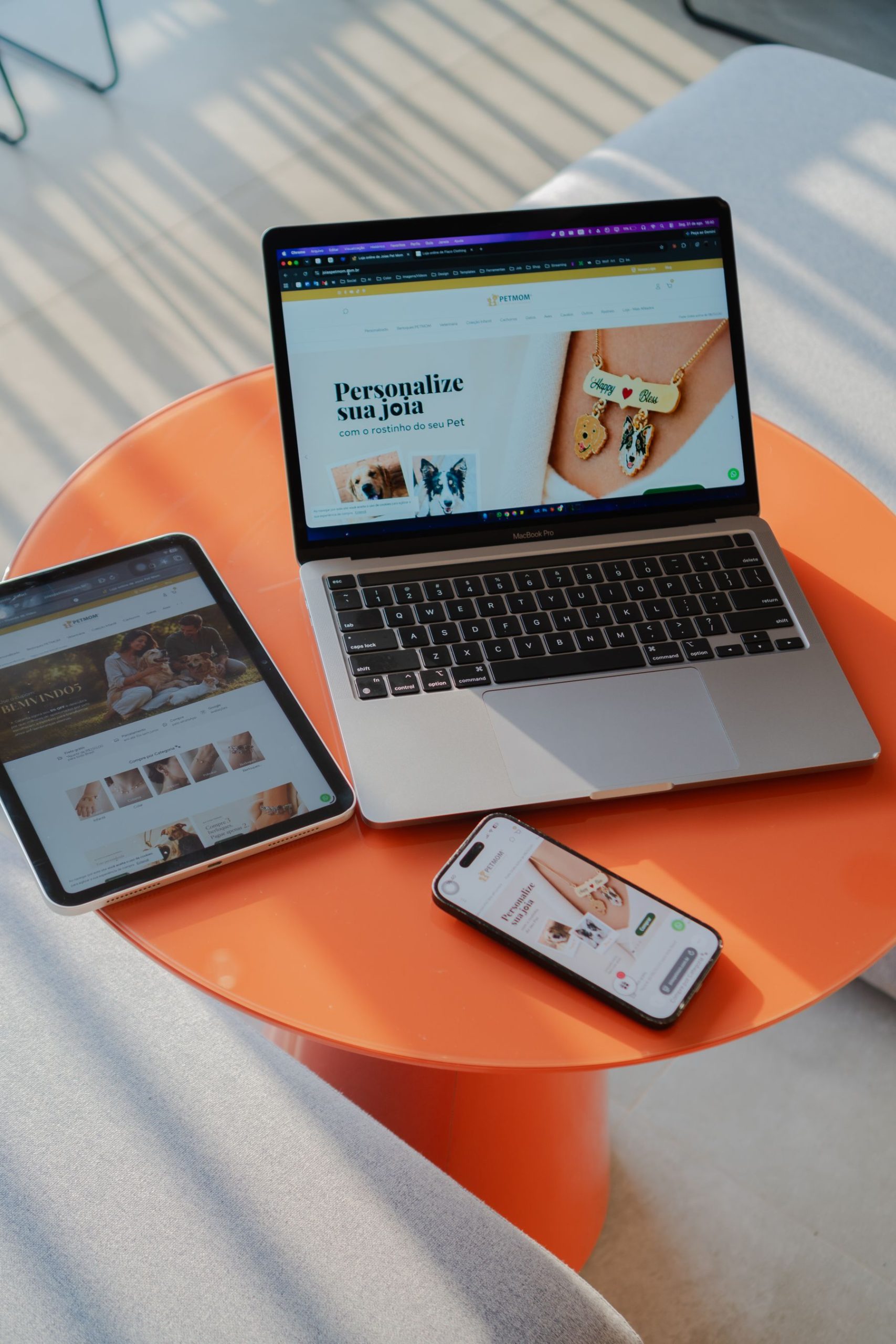 Portátil, tableta y móvil mostrando sitios web sobre una mesa naranja